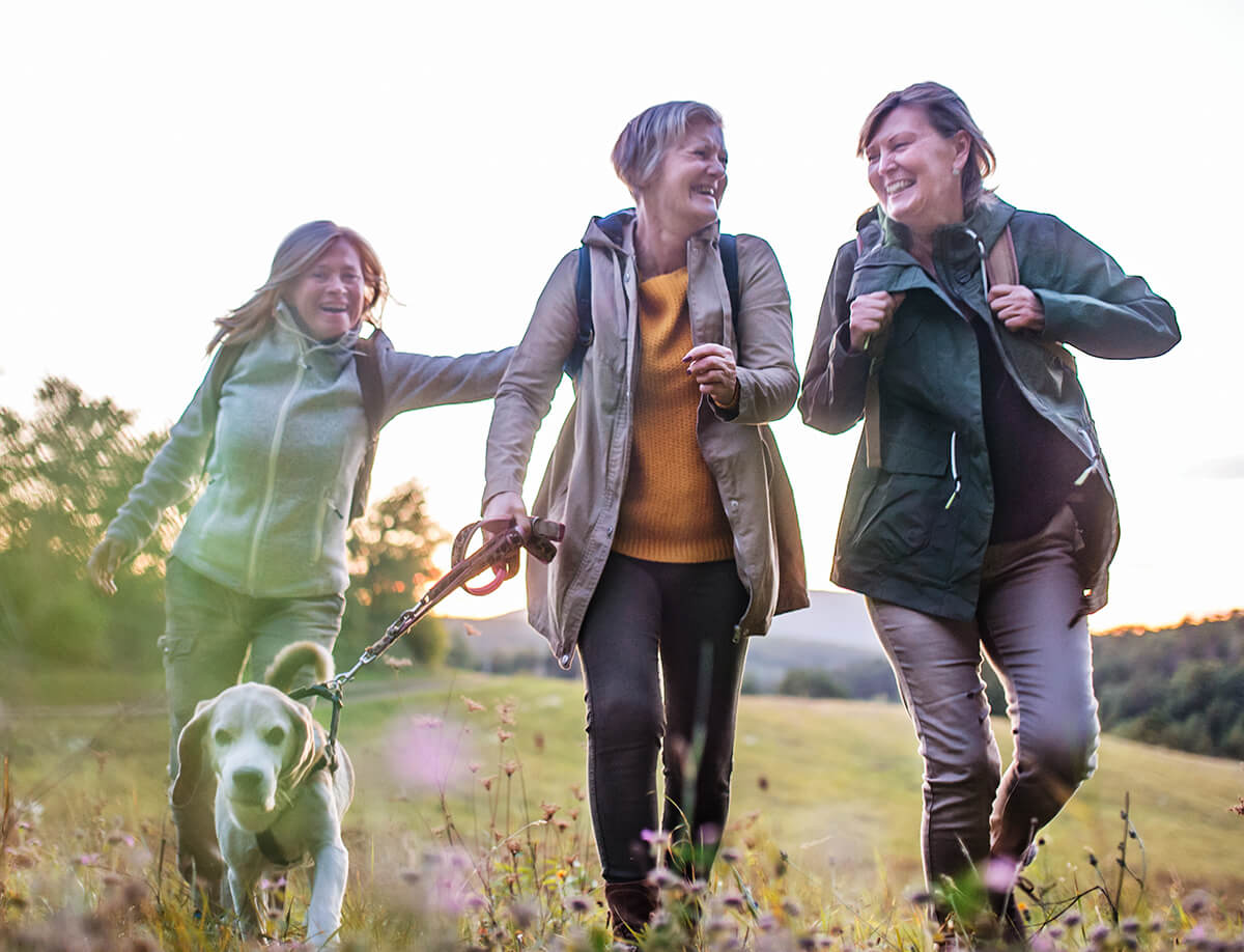 Three elderly women walking a dog